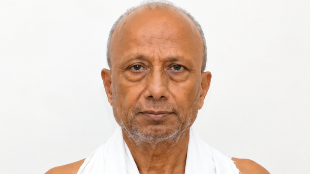 Portrait of an older man with a light beard, wearing a white cloth around his shoulders, against a plain light background.