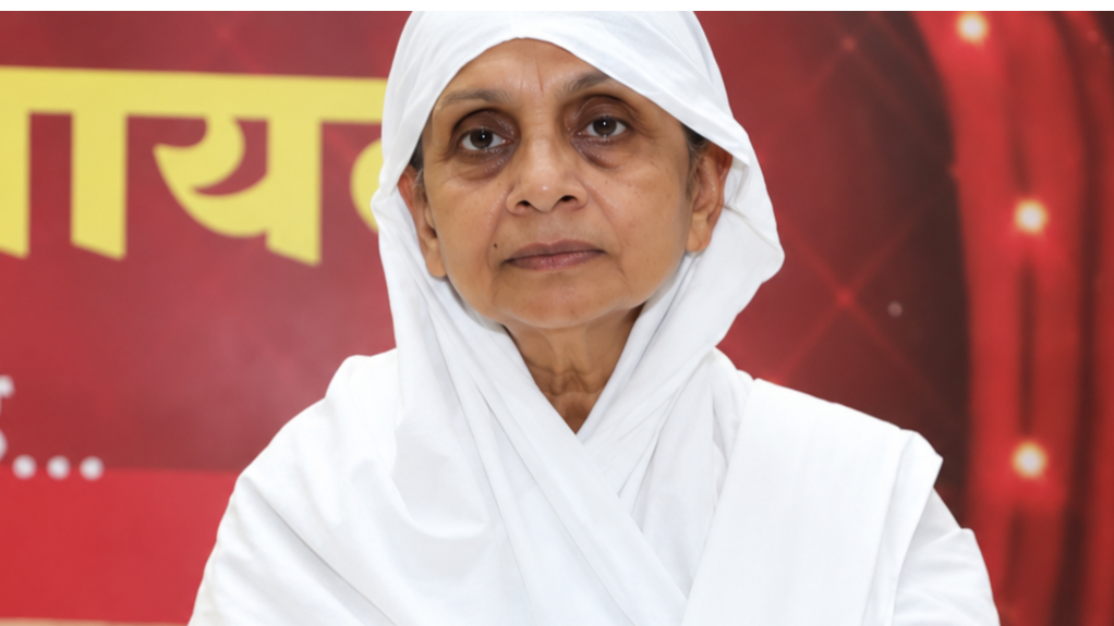 Portrait of a woman in a white headscarf and robes against a red backdrop.