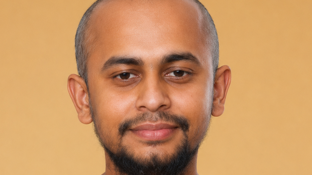 Close-up portrait of a man with short hair and a trimmed beard, smiling slightly against a warm yellow background.