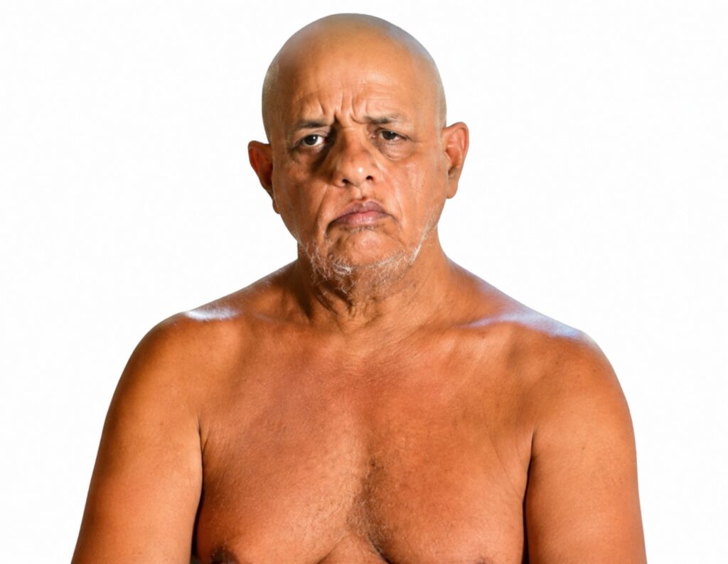 Bald, middle-aged man with a gray beard, shirtless, looking solemn against a plain white background.