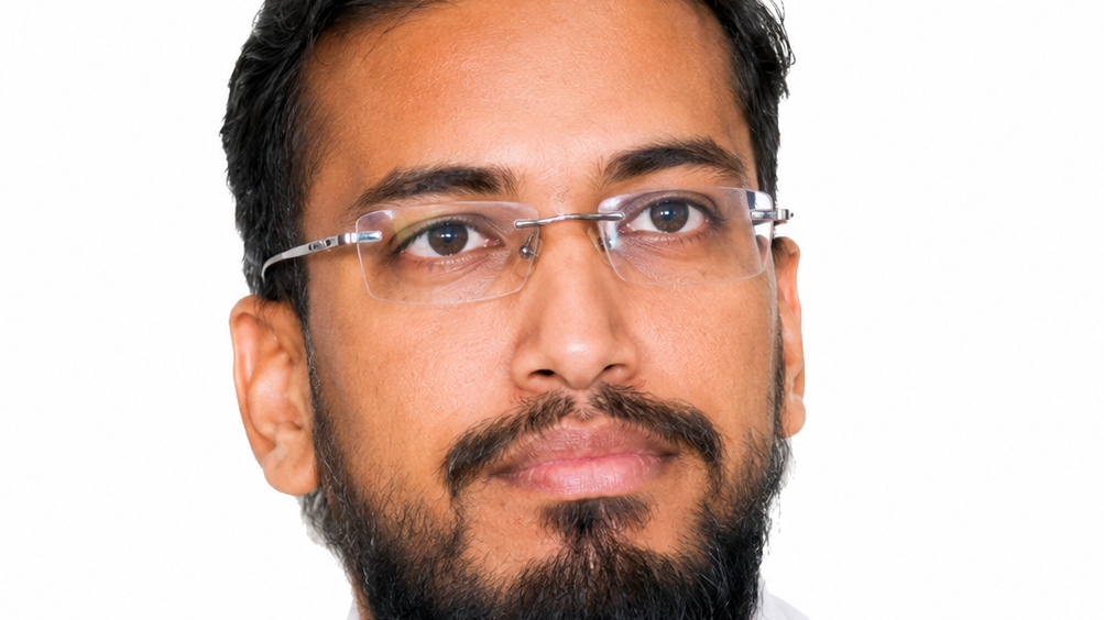Close-up portrait of a man with glasses and a beard looking slightly to the left.