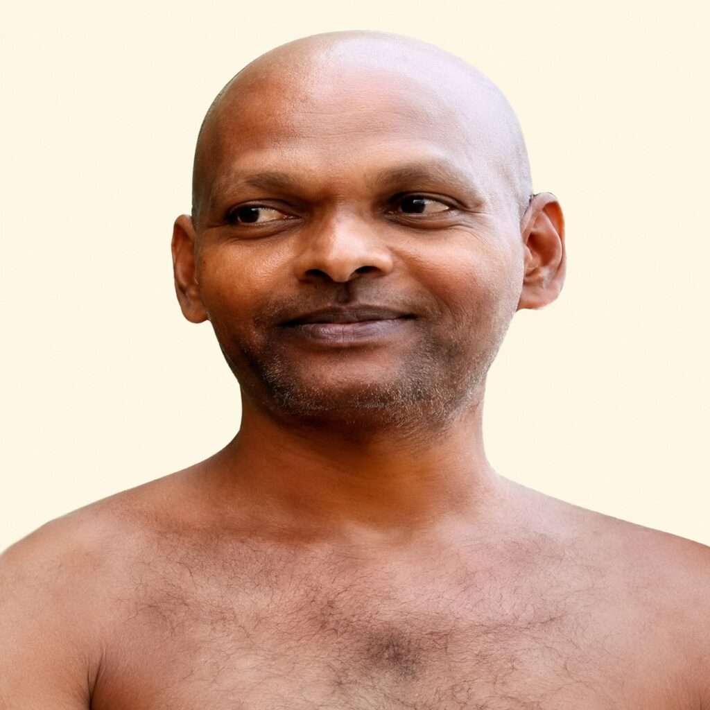 Smiling man with a shaved head and bare shoulders against a light backdrop (portrait).