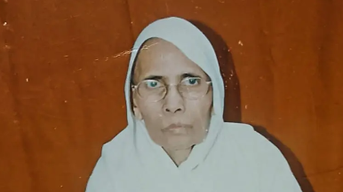 Portrait of a woman wearing a white headscarf against an orange background.
