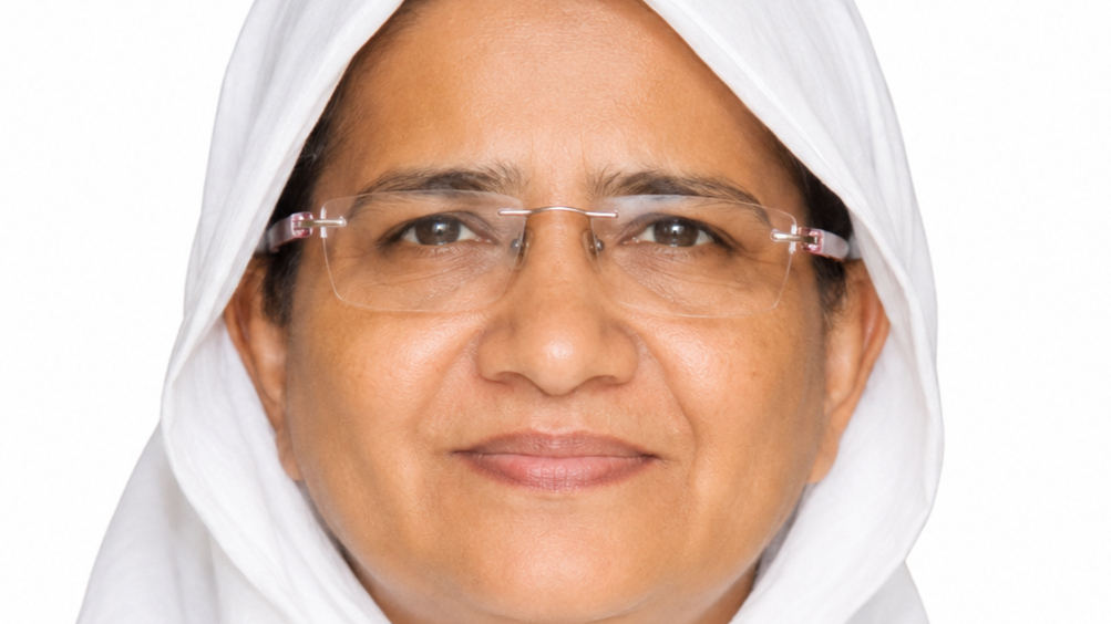 Close-up portrait of a smiling woman wearing a white headscarf and transparent glasses.