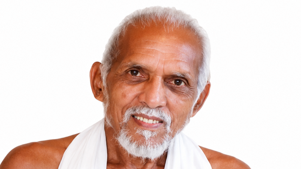 Older man with white hair and beard smiling at the camera, wearing a white robe against a plain white background.