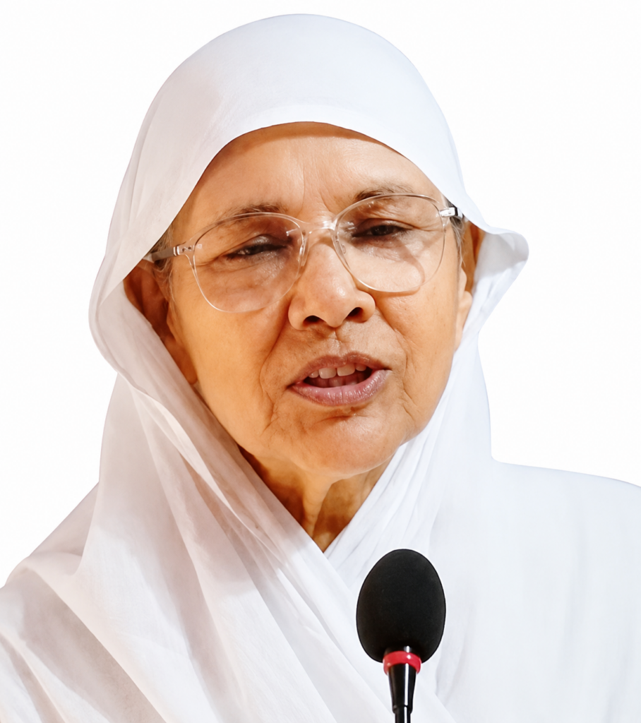 Older woman in a white headscarf and glasses speaking into a microphone in front of a white background.