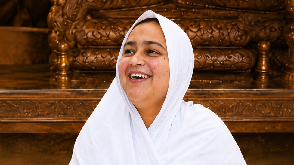 Young woman wearing a white hijab smiles warmly in front of intricately carved wooden furniture.