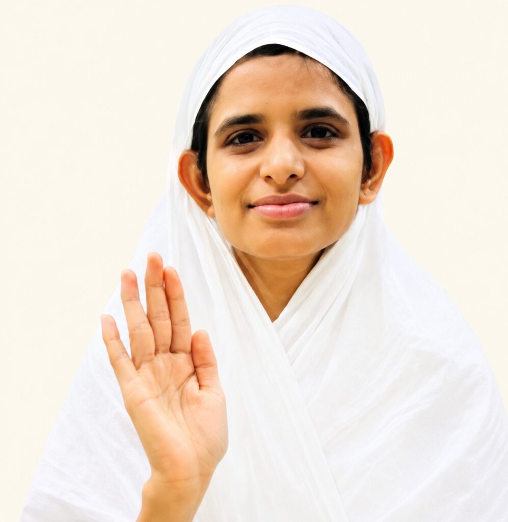 Young girl in a white hijab smiling and raising her hand in greeting toward the viewer