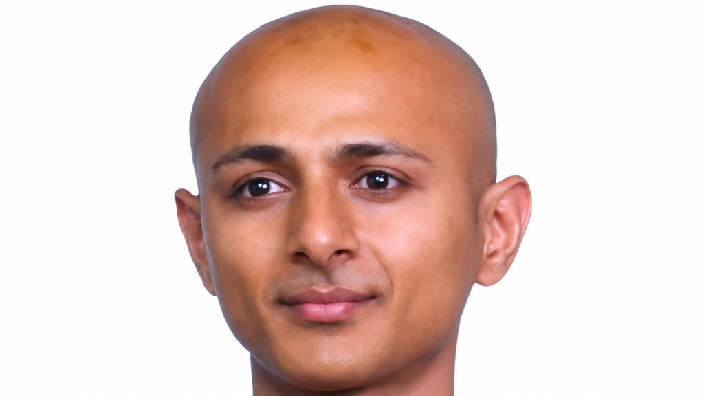 Close-up headshot of a bald man with a neutral expression against a white background.
