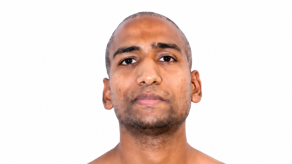 Close-up portrait of a man with a neutral expression against a white background.