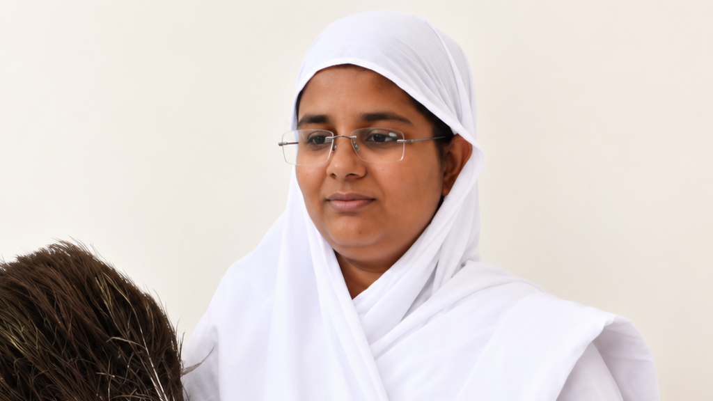 Woman in a white hijab and glasses looks at a head of brown hair in front of her, thoughtful expression.