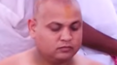 Person with shaved head meditating, eyes closed.