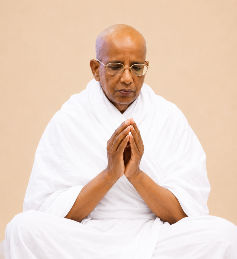 Monk in white robes sitting cross‑legged with hands pressed together in prayer, eyes closed in meditation.