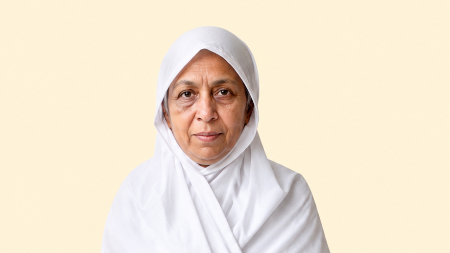 Portrait of an older woman wearing a white hijab, facing the camera against a pale beige background.