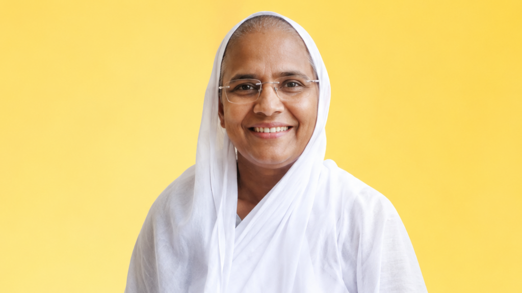 Smiling woman in a white headscarf and glasses against a bright yellow background.