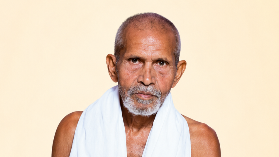 Portrait of an older man with a gray beard, bare shoulders, wearing a white cloth, looking directly at the camera against a beige background.