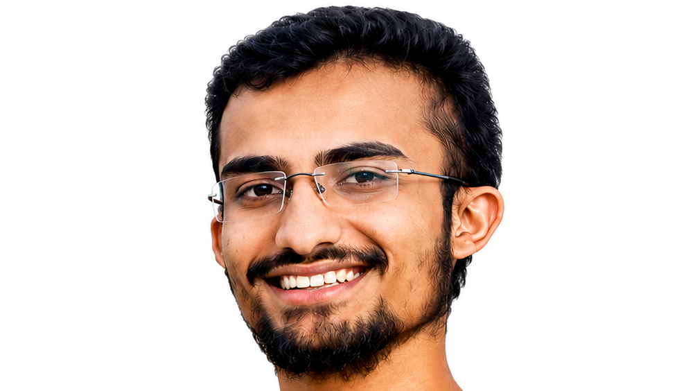 Portrait of a smiling man with dark hair and a beard wearing metal-rimmed glasses, facing the camera.